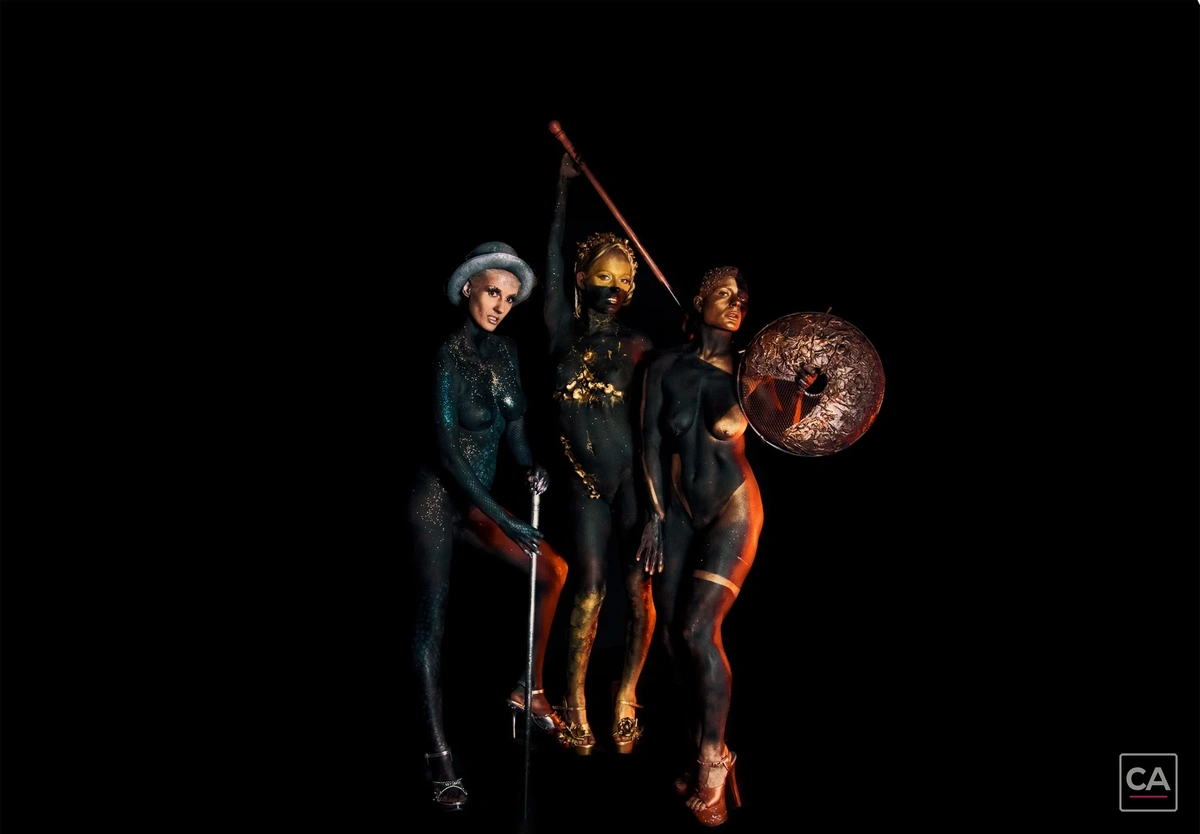 Drei Models mit farbigem Bodypainting vor schwarzem Hintergrund