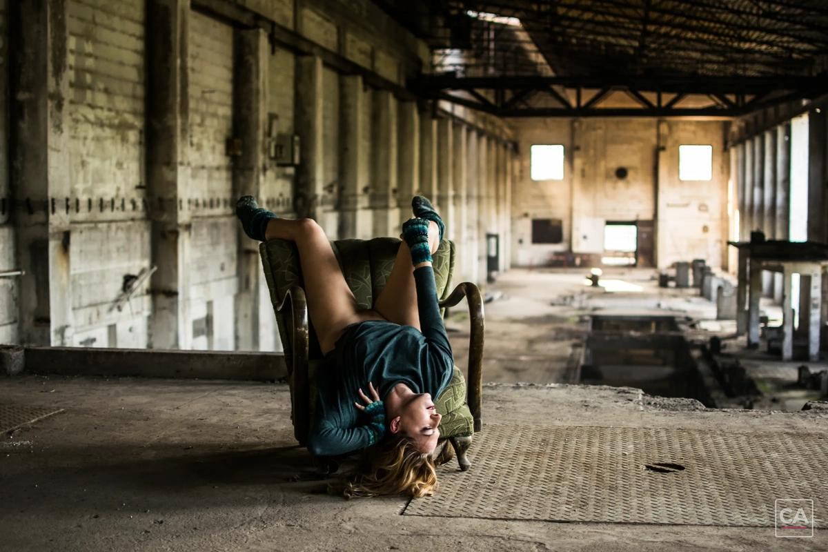 Model kopfüber im Sessel in einer Industriehalle