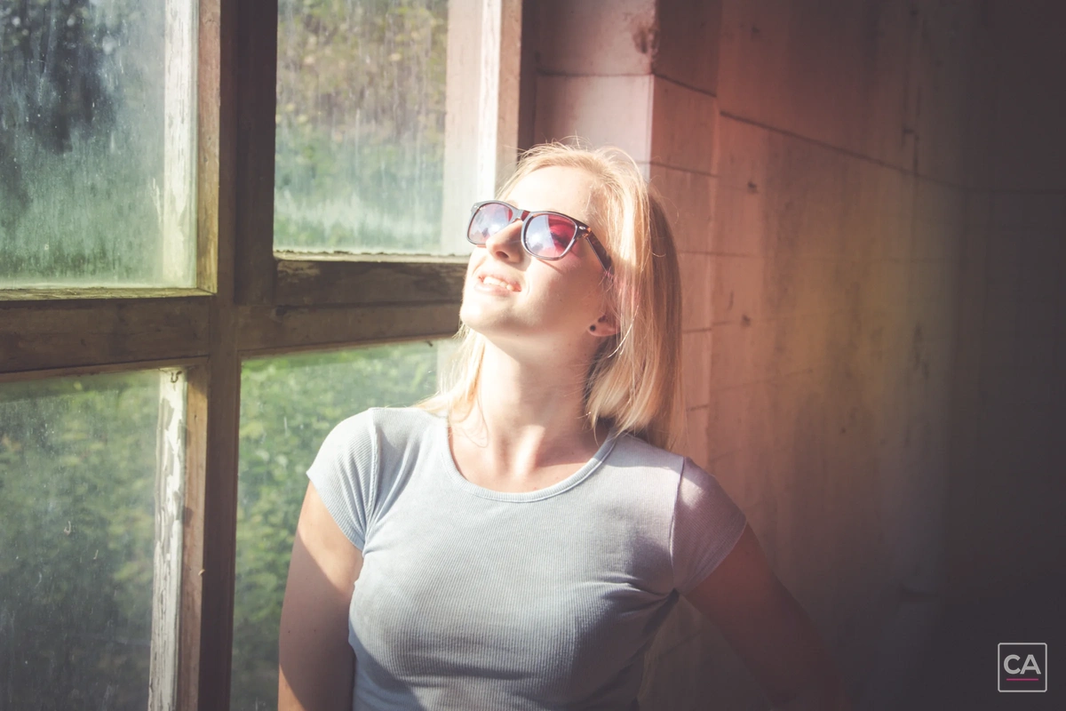 Portrait mit Sonnenbrille vor einem Fenster