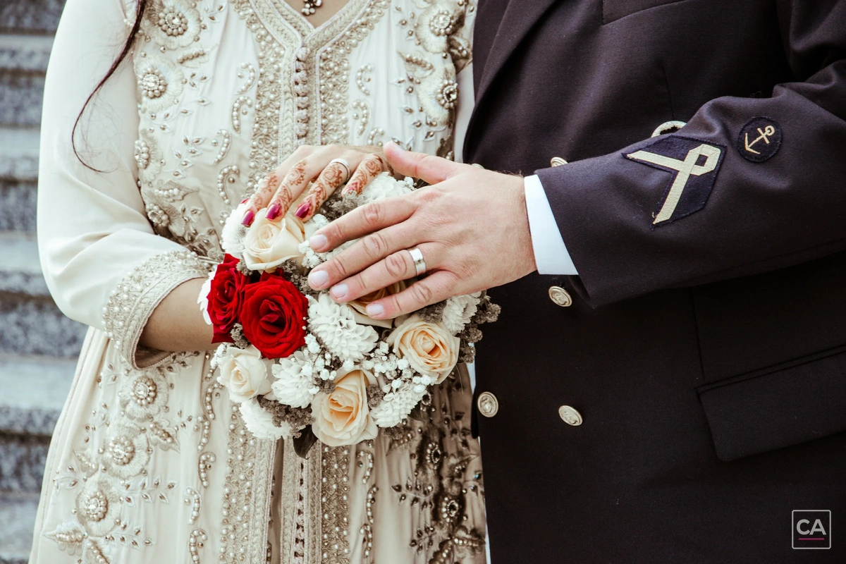 Hände eines Hochzeitspaars mit Blumenstrauß